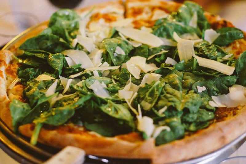 woodfired pizza topped with spinach served during North Beach food tour